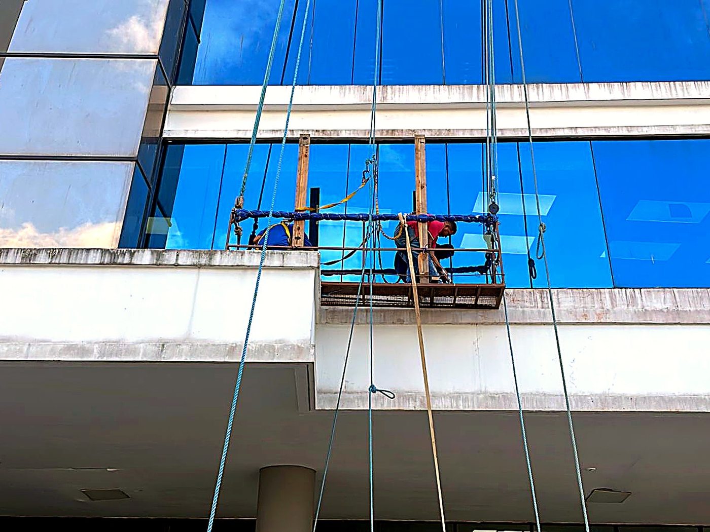 Cuadrilla instalando fachada de vidrio en góndola suspendida